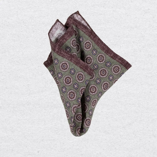 Pistachio green linen pocket square with brown medallion motif on a grey
background