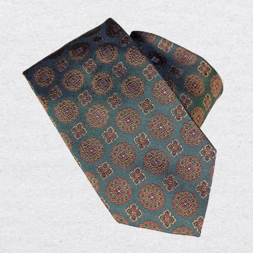 Dark coloured silk tie with brown medallion patterns, on a white background