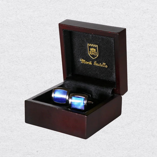Blue cufflinks in a wooden box with 'Monti Castello' branding on a light gray background
