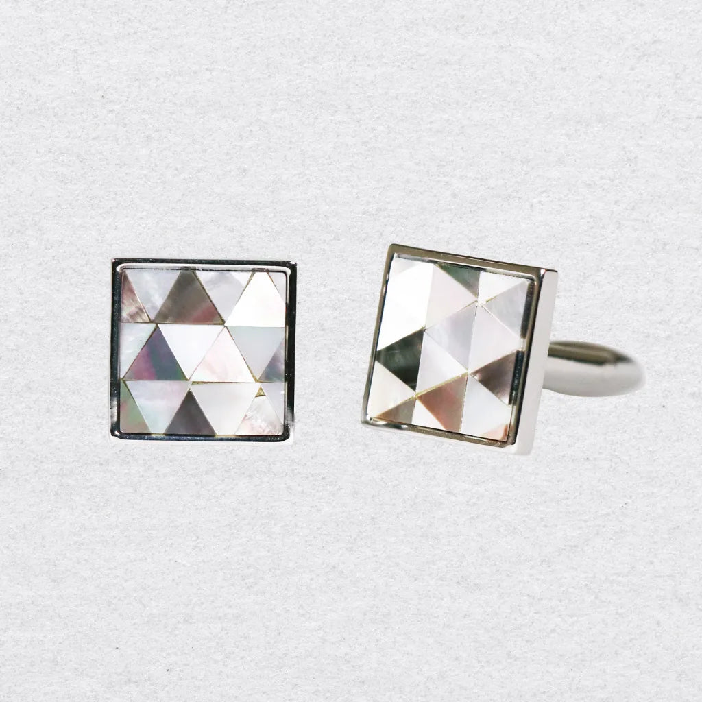 Two square cufflinks with a mosaic mother of pearl design on a grey background