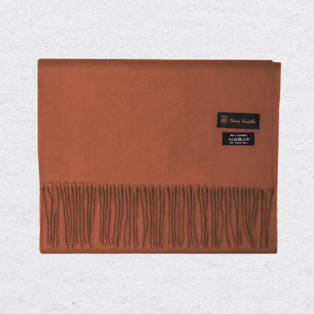 Orange cashmere scarf with fringes on a light gray background