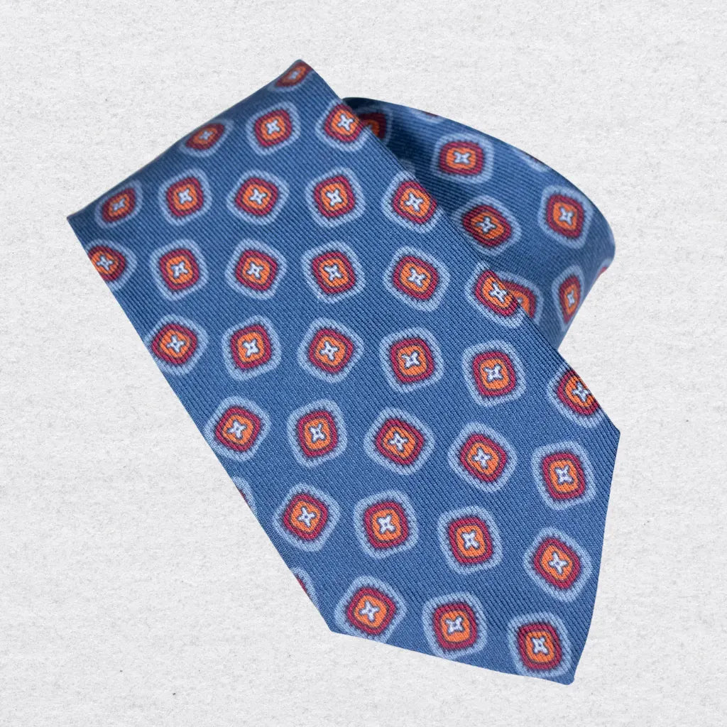 Blue wool-silk tie with orange pattern, rolled on a white background