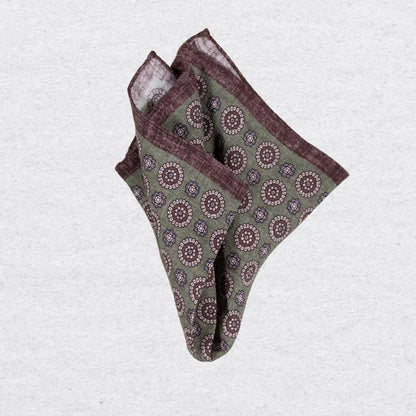 Pistachio green linen pocket square with brown medallion motif on a grey 
background