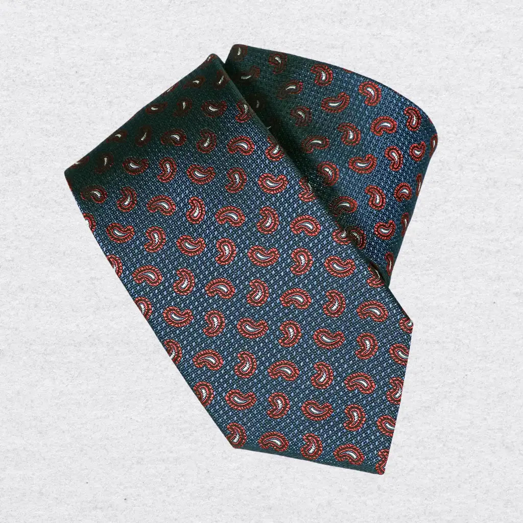 Navy silk tie with red paisley pattern, rolled on a white background