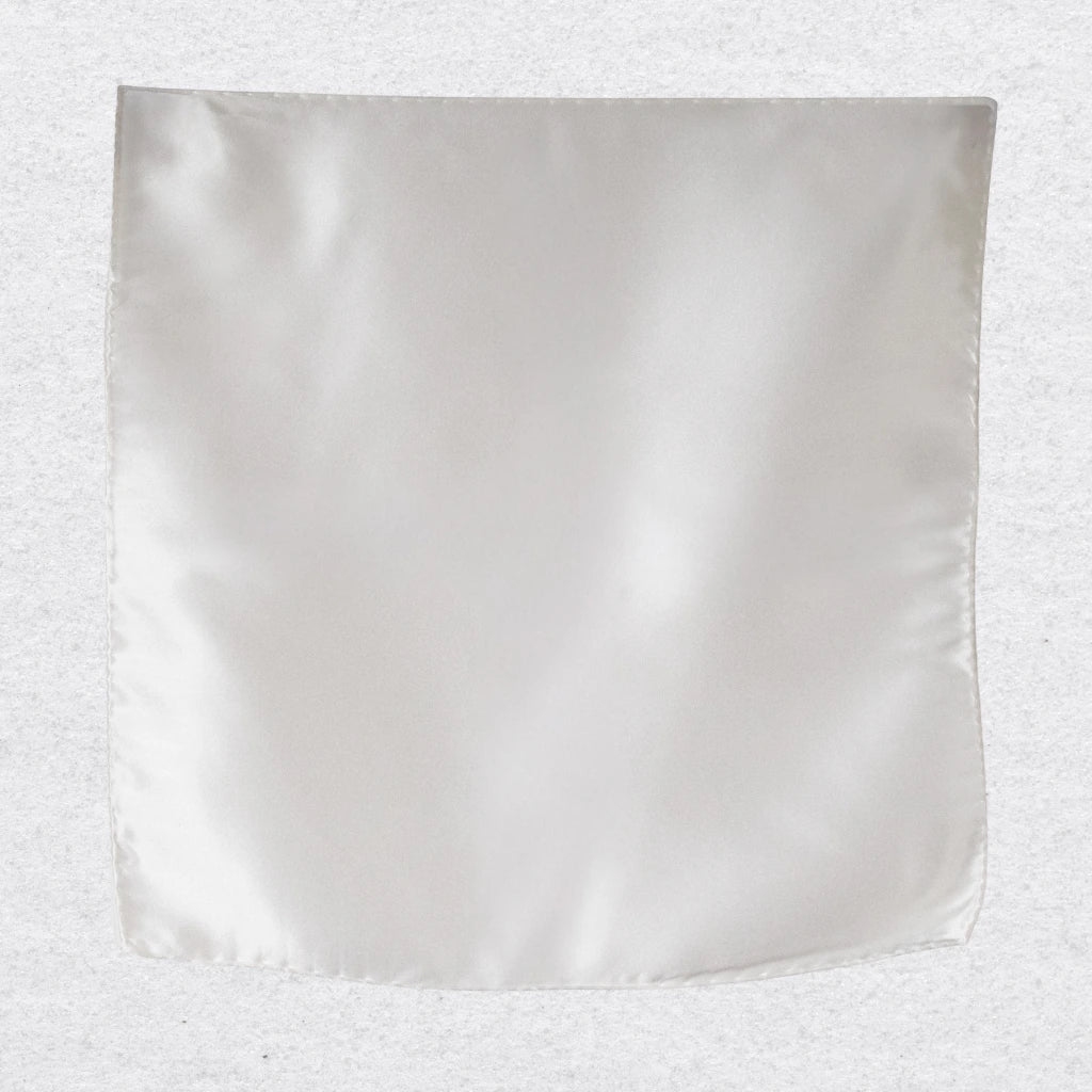 White silk pocket square hanging against a textured grey background