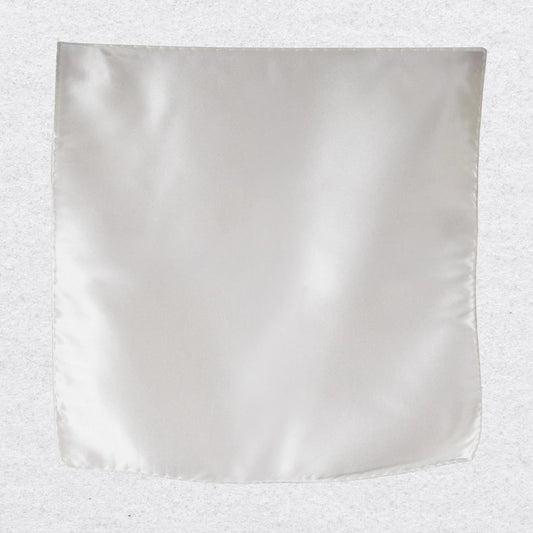 White silk pocket square hanging against a textured grey background