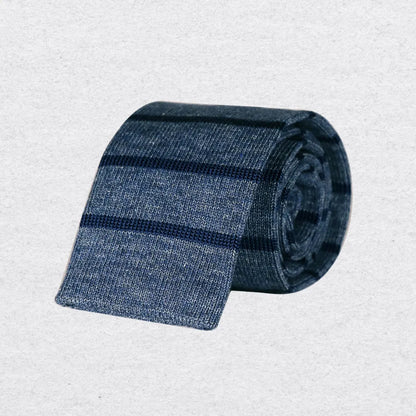 Blue striped knitted tie rolled up on a textured  background