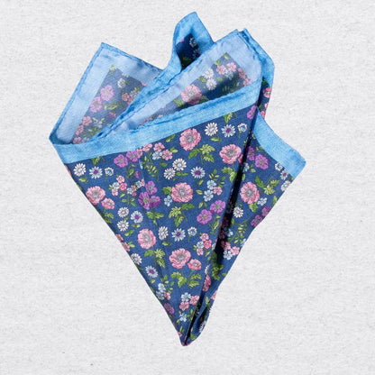 Floral patterned silk pocket square with blue border on a grey background