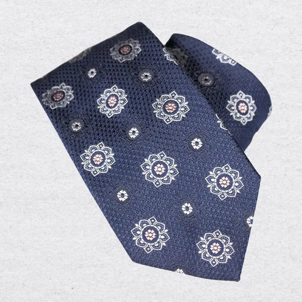 Navy textured silk tie with white rosette motif, rolled on a white background
