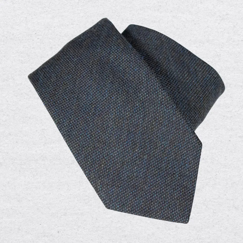 Navy and dark green wool-silk tie, rolled on a white background