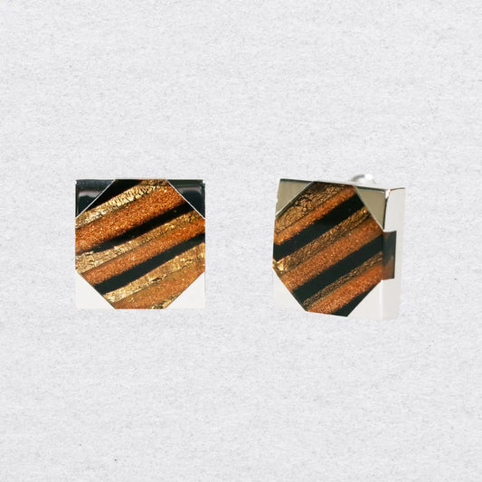 Pair of square cufflinks with gold and black tiger stripe design on a grey background