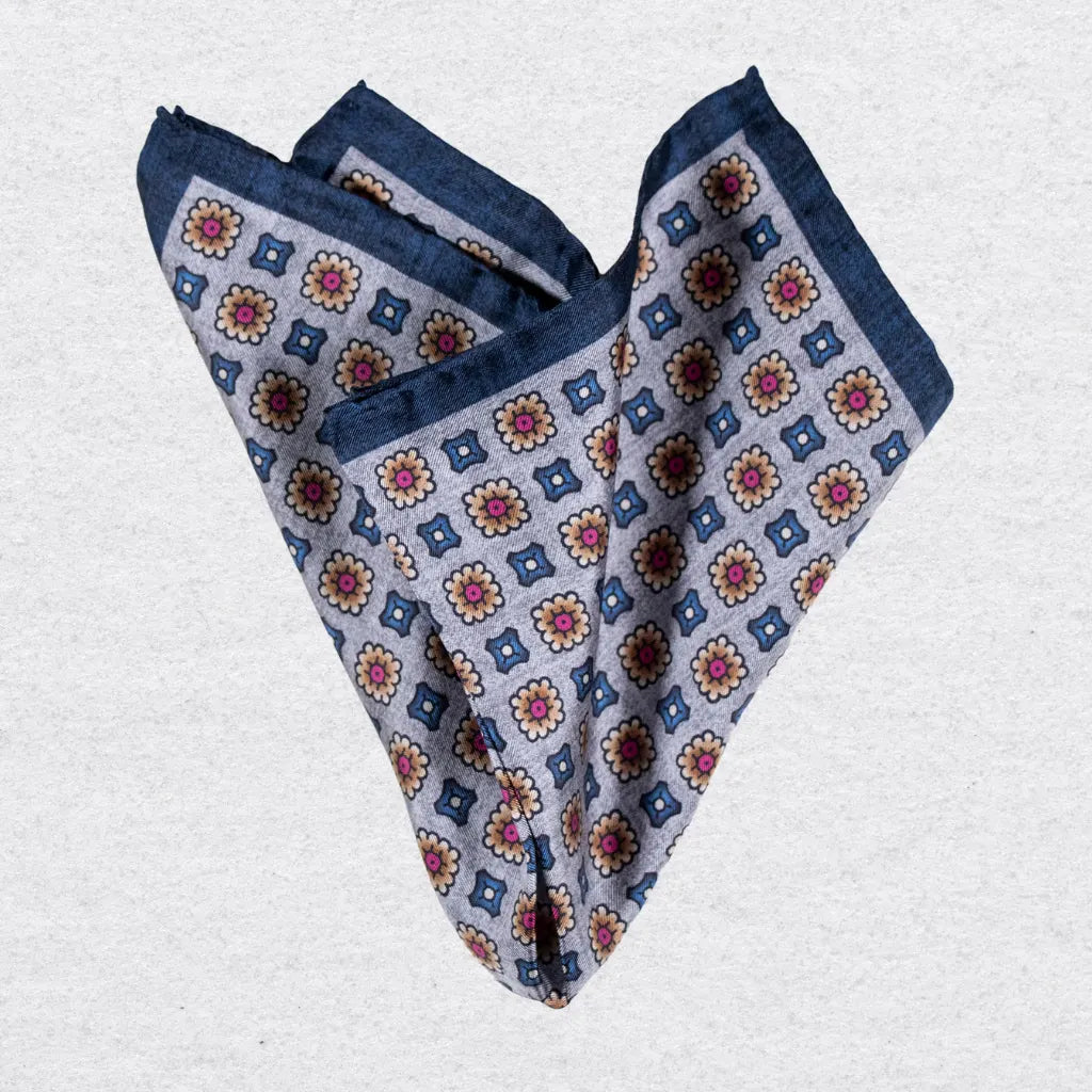 Folded pocket square with a medallion pattern on a grey background