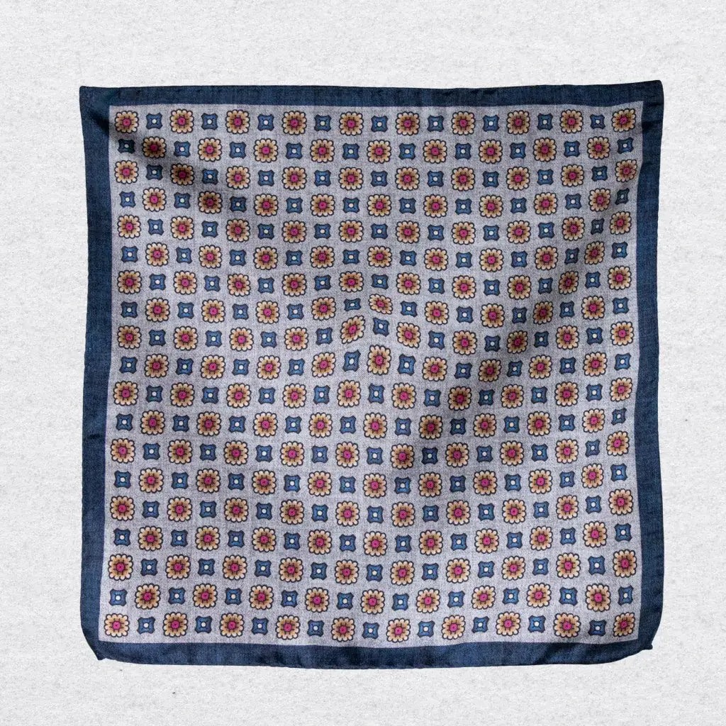 Pocket square with a medallion pattern hanging against a grey background