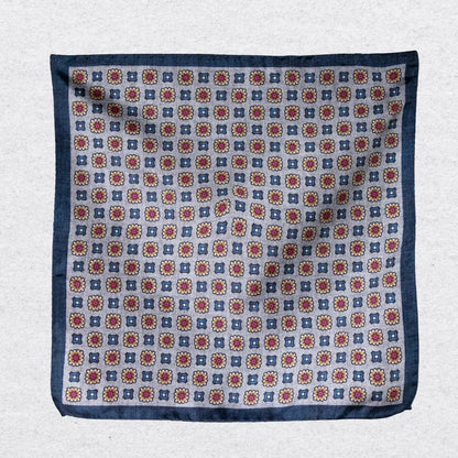 Pocket square with a medallion pattern hanging against a grey background