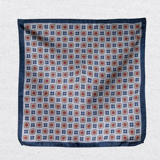 Pocket square with a medallion pattern hanging against a grey background