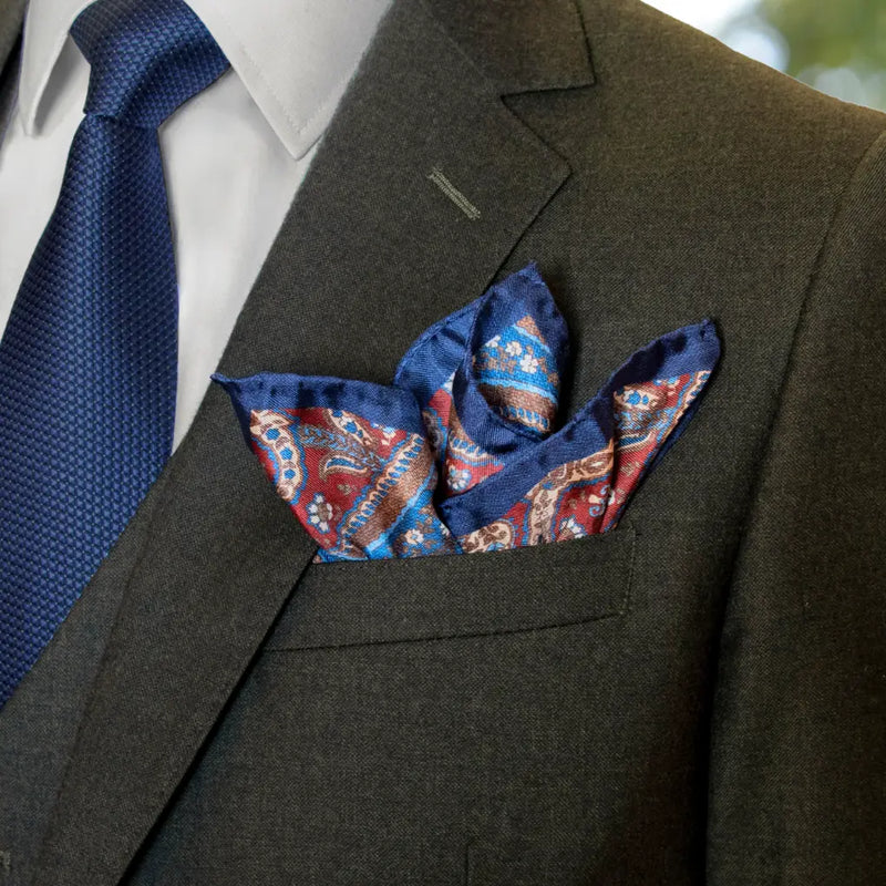 Olive green suit with blue tie and patterned pocket square
