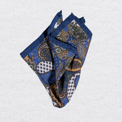 Blue and gold paisley pocket square on a grey background