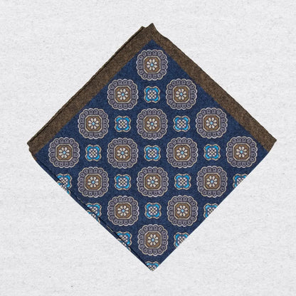 Navy blue pocket square with brown and beige floral medallion pattern on a grey background