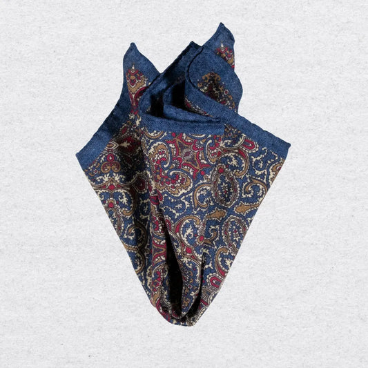 Dark blue paisley pocket square on a light grey textured background