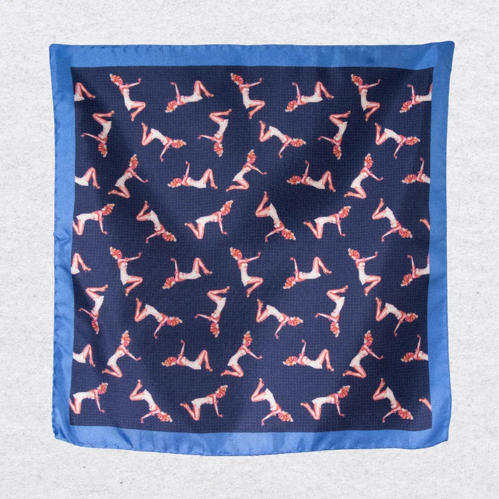 Navy blue silk pocket square with pink pin-up girls, hanging against a grey background