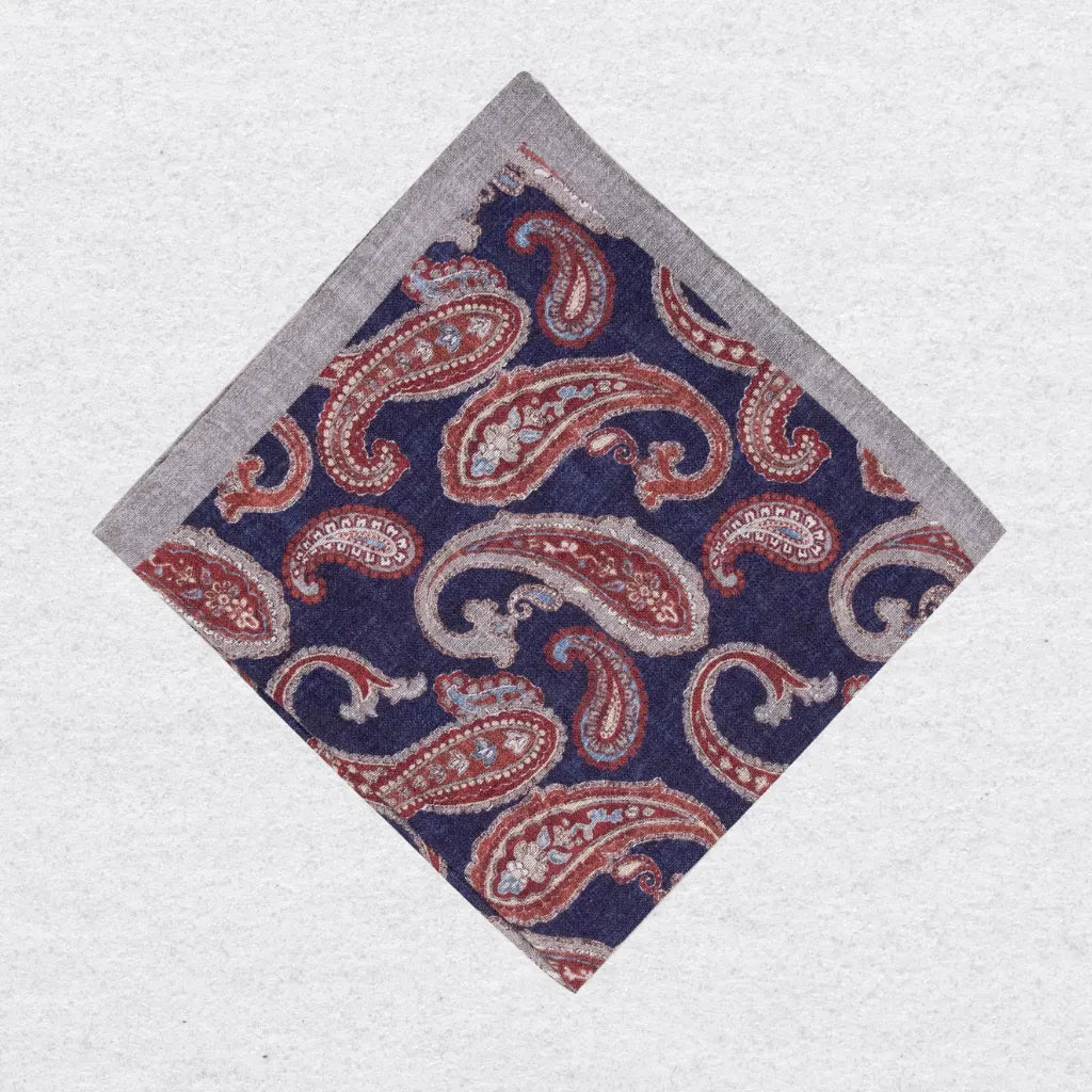 Paisley patterned linen pocket square in navy and rust on a white background