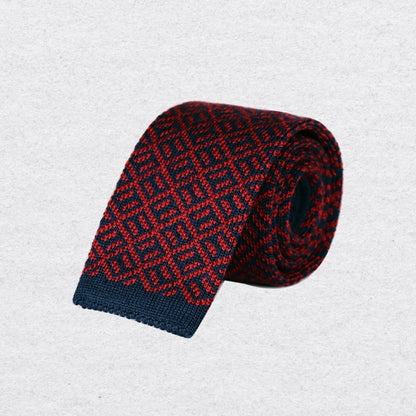 Navy and red patterned knitted tie rolled on a textured background