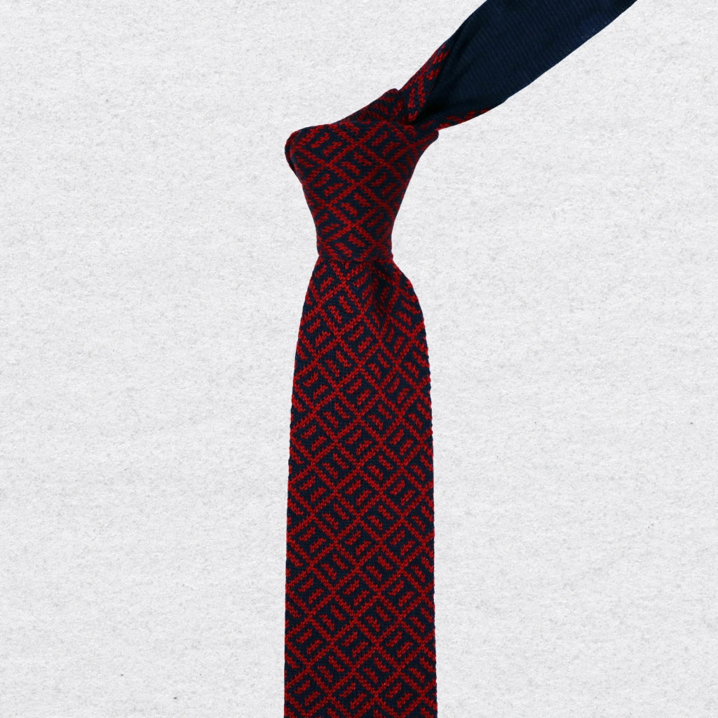 Navy and red patterned knitted tie on a textured background