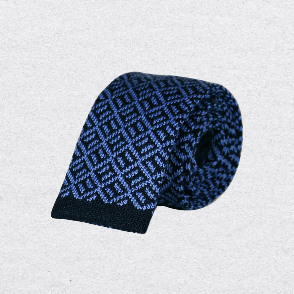 Navy and sky blue patterned knitted tie rolled on a textured background
