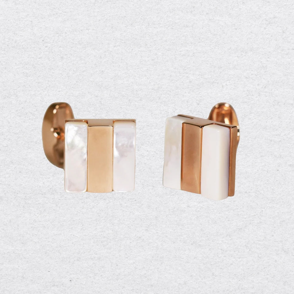 Pair of cufflinks with rose gold and mother of pearl design on a grey background
