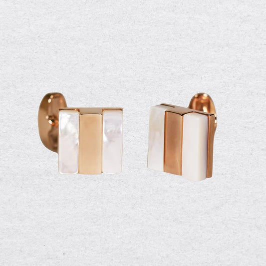 Pair of cufflinks with rose gold and mother of pearl design on a grey background