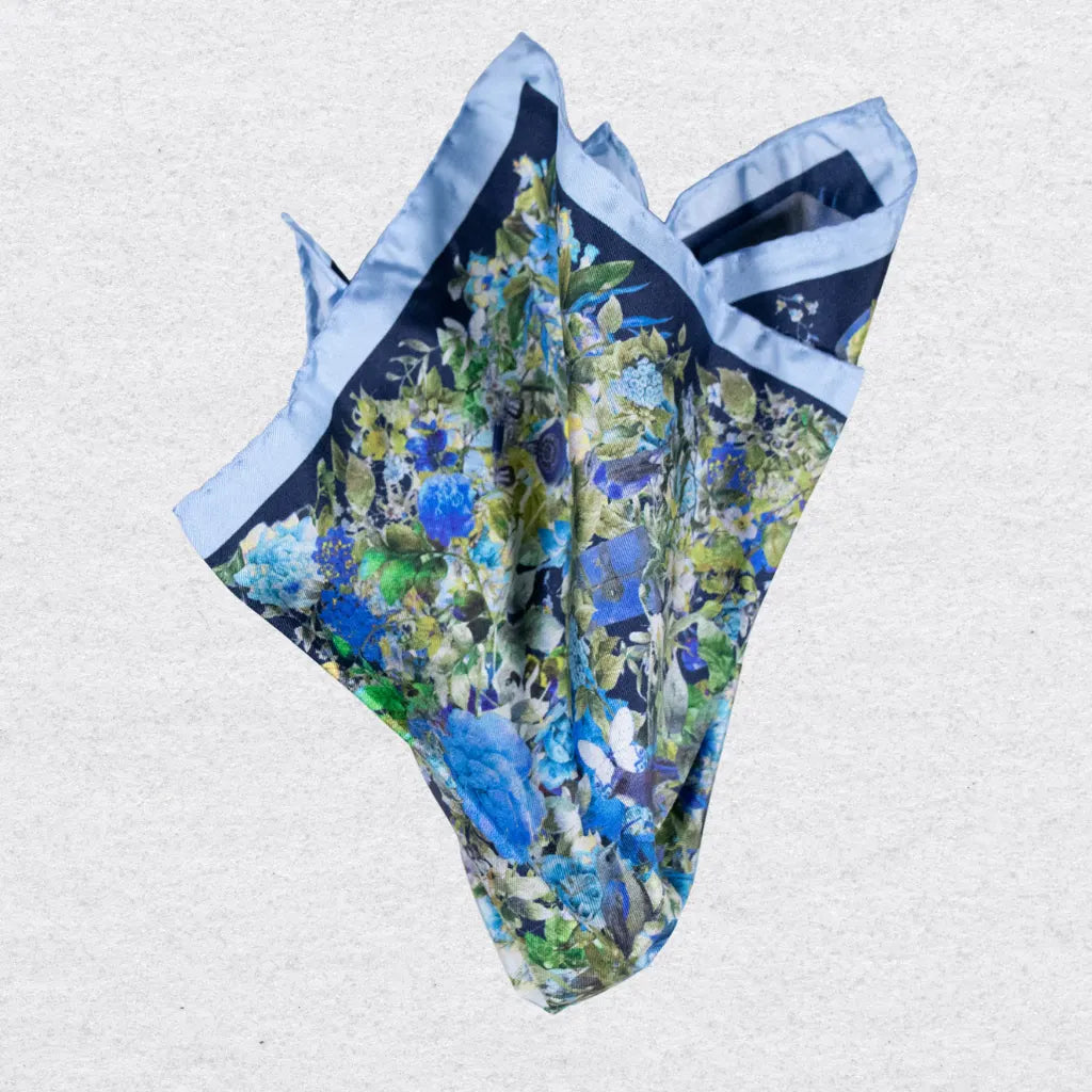 Blue floral pocket square pinched on a grey background