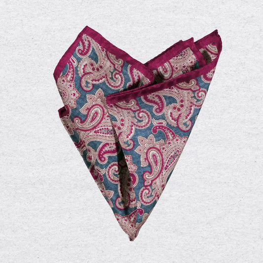 Red and blue paisley patterned silk pocket square on a grey background