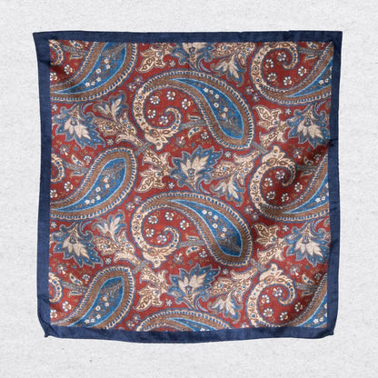 Rustic navy paisley silk pocket square hanging against a light grey background