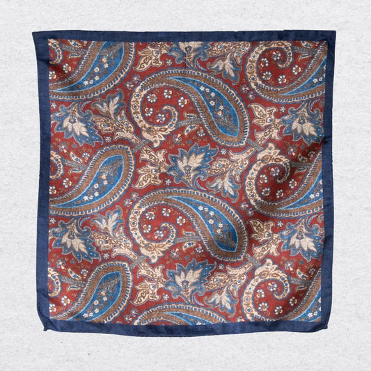 Rustic navy paisley silk pocket square hanging against a light grey background