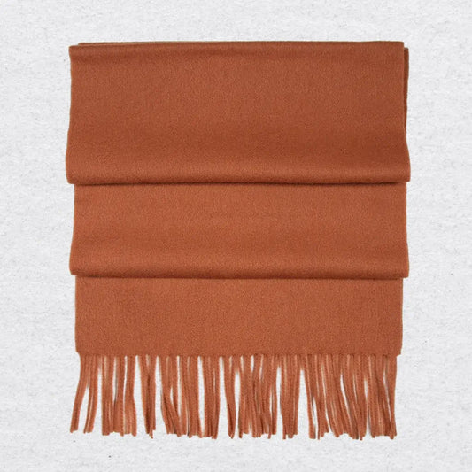 Burnt orange cashmere scarf with tassels on a light gray background