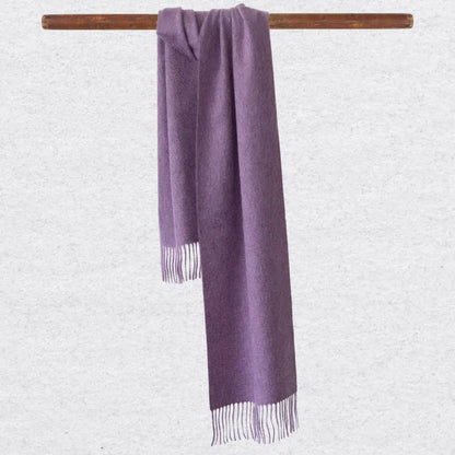 Lilac cashmere scarf with tassels on a wooden rod against a light gray background