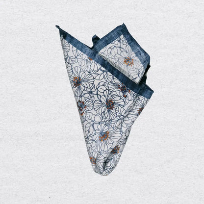 Floral patterned pocket square with blue border pinched on a textured grey background