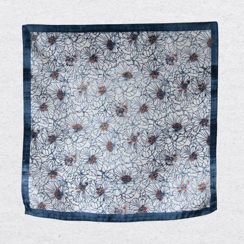 Floral patterned silk pocket square hanging against a textured grey background