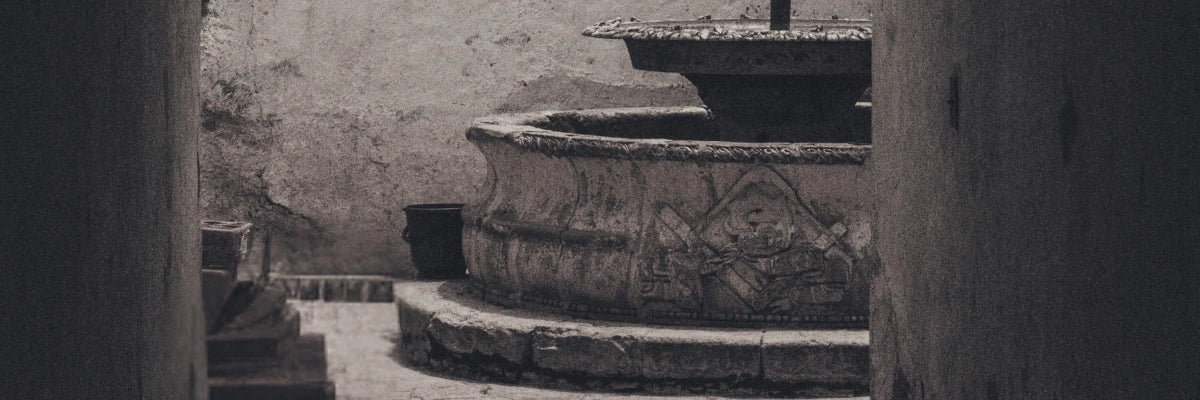 Decorative stone fountain with intricate patterns in a rustic setting