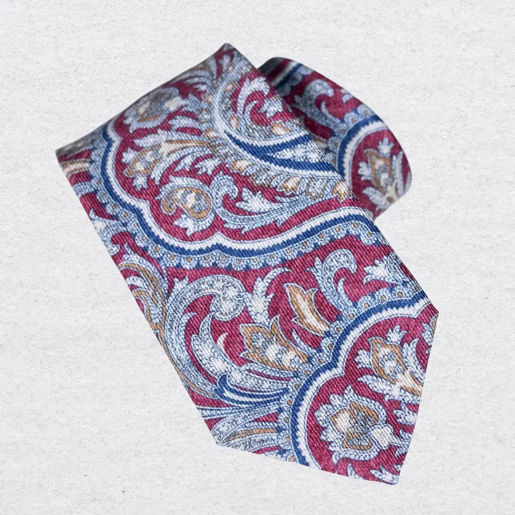 Patterned wool-silk tie with red, blue, and beige paisley design on a white background