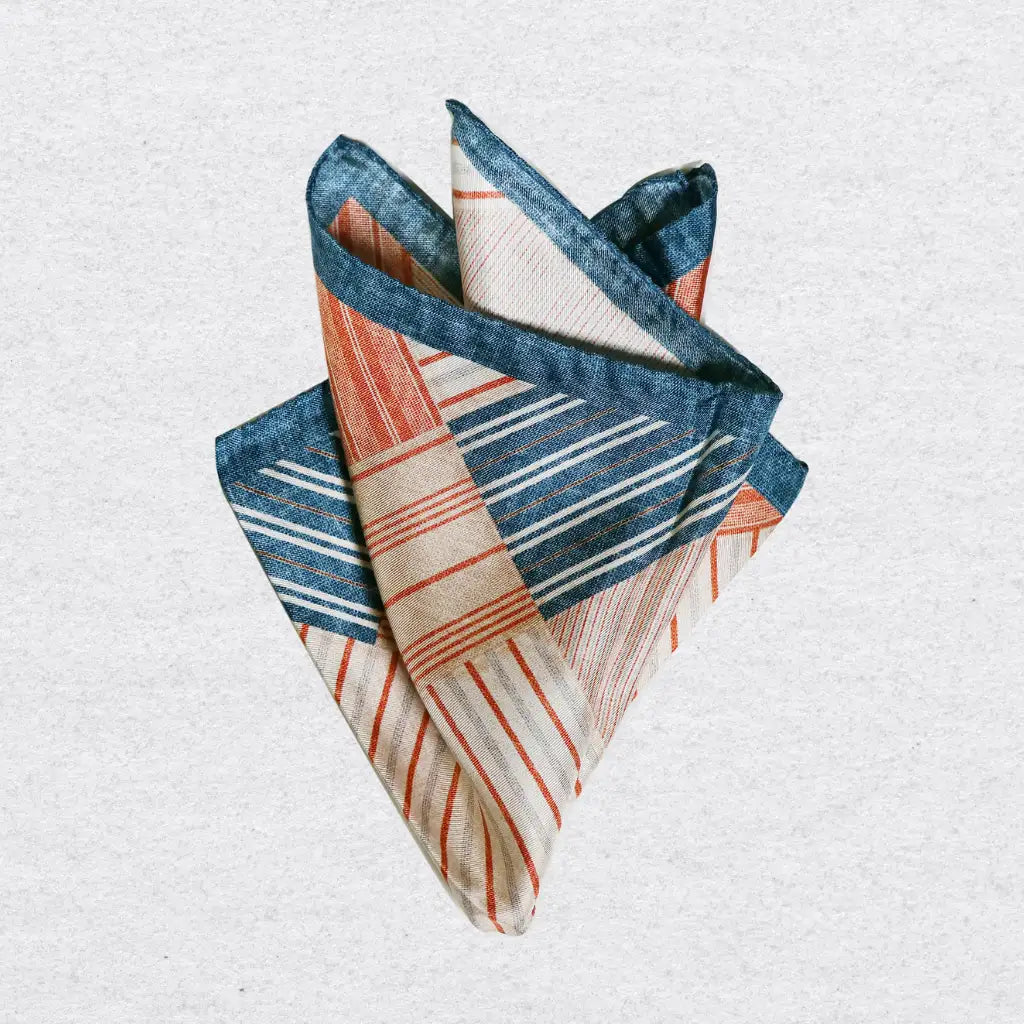 Striped patchwork silk pocket square pinched on a light grey background