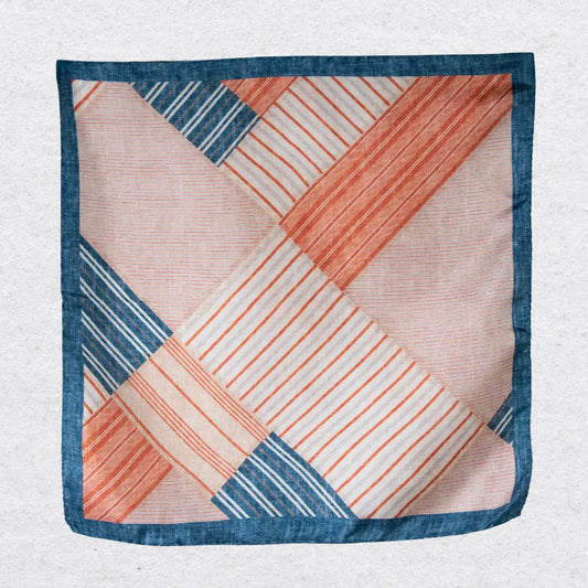 Patchwork patterned pocket square with orange, blue, and beige colors on a grey background
